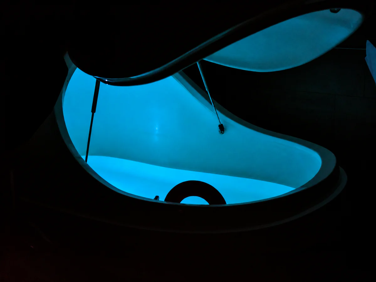 Teal-lit open float pod at Serenus